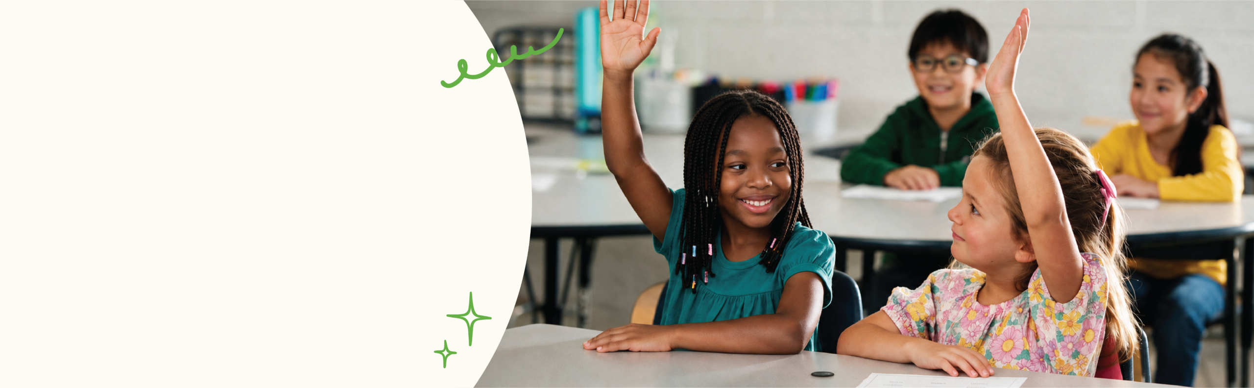 two girls smiling while raising their hands in a classroom