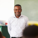 Male teacher smiling at camera in classroom